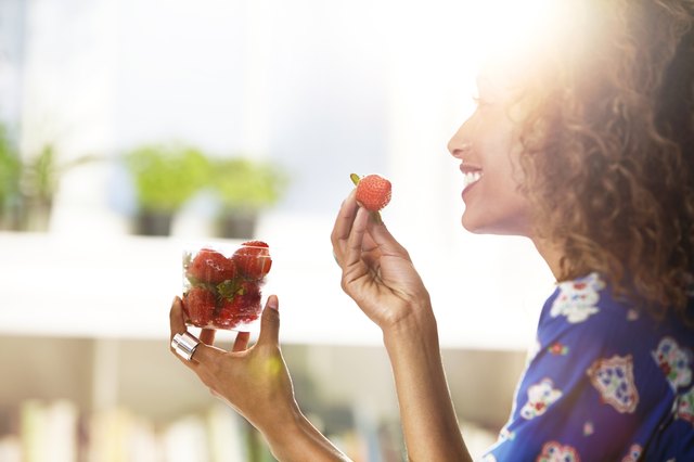 Woman eating strawberries at home.