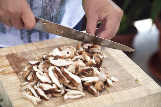 Woman's hands slicing mushrooms.