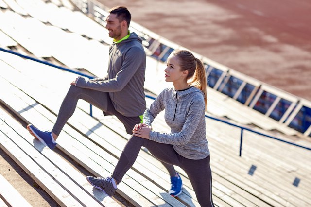 couple stretching leg on stands of stadium