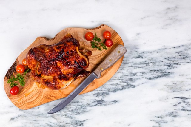 Large whole chicken ready to be served on wooden board