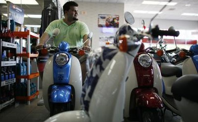 Man looking at Honda scooters on showroom floor.