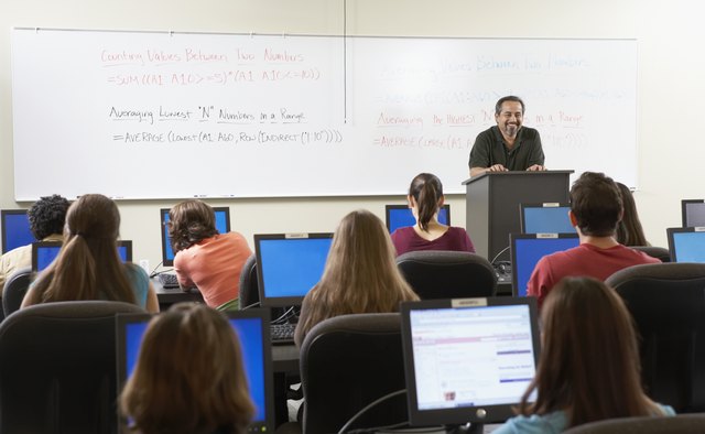 Rear view of a group of students sitting in front of computer monitors