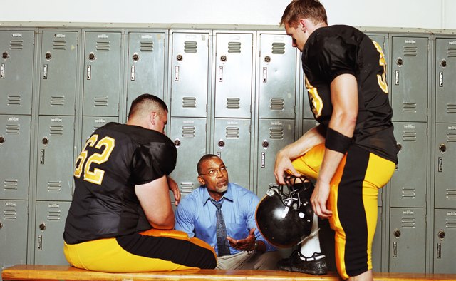 Football players listening to coach in locker room
