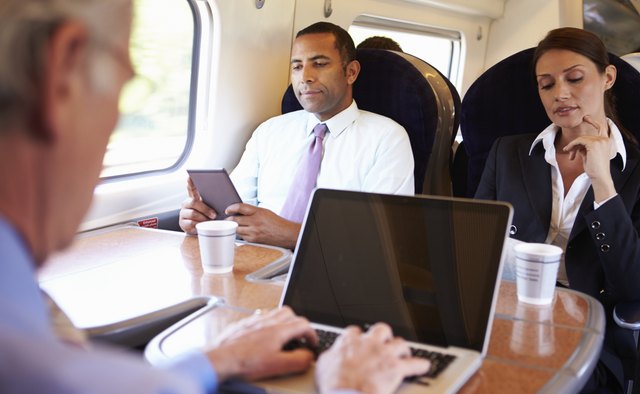 Businessman Commuting To Work On Train And Using Laptop