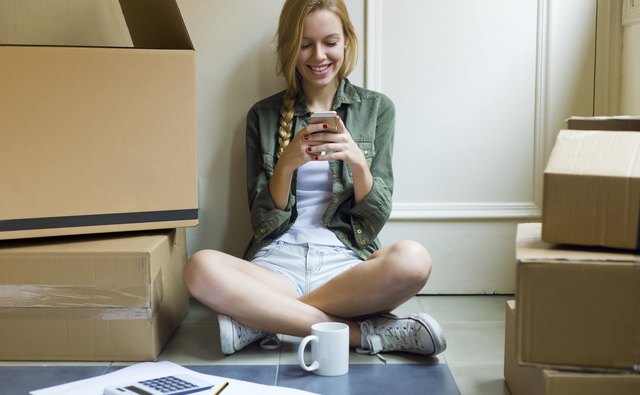 Young beautiful woman with mobile phone in her new house.