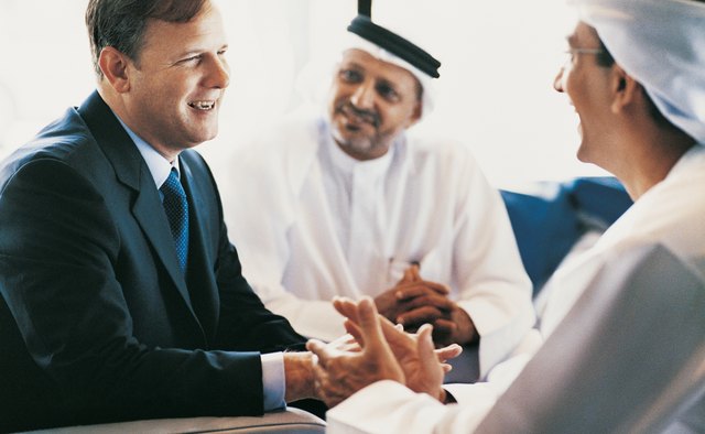 Businessman Having a Discussion With Two Other Businessmen Wearing Traditional Middle Eastern Dress