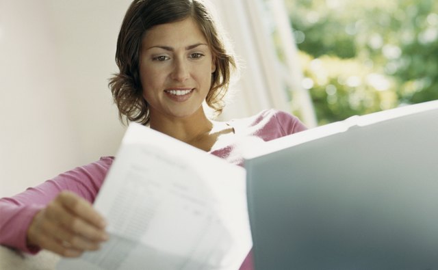 Smiling Woman Sits Behind her laptop Reading a Bill