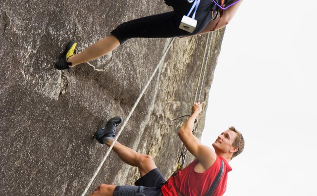 Couple rock climbing on steep cliff