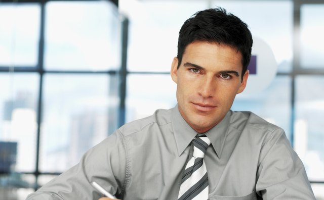 Portrait of a young businessman sitting at a table with a pen and paper