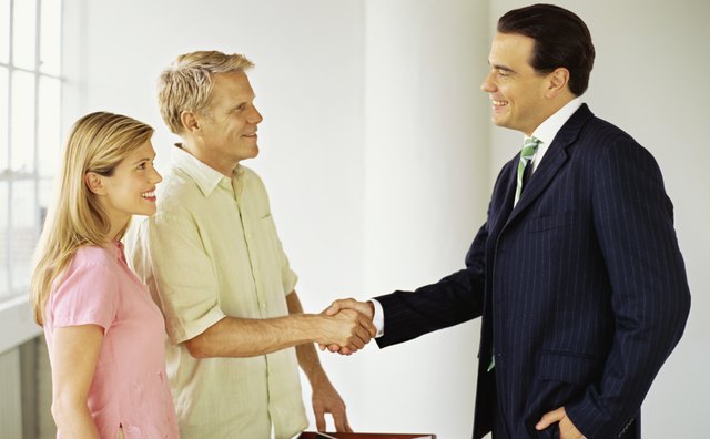 side profile of a male real estate agent shaking hands with a mid adult man