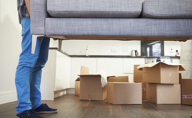 Man Carrying Sofa As He Moves Into New Home