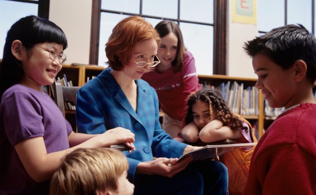 Teacher reading book to children (8-9), in school classroom