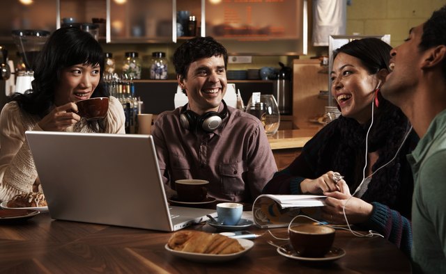 Four adults sitting at table in cafe, talking and laughing