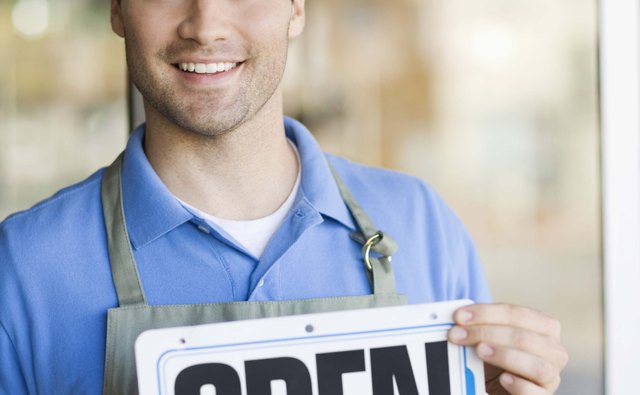 Shopkeeper smiling by storefront with open sign