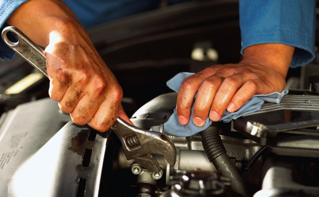 Hands of mechanic fixing engine