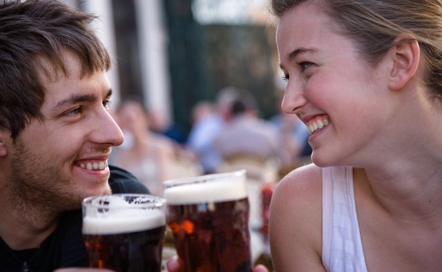 Young woman and man toasting beers outdoors