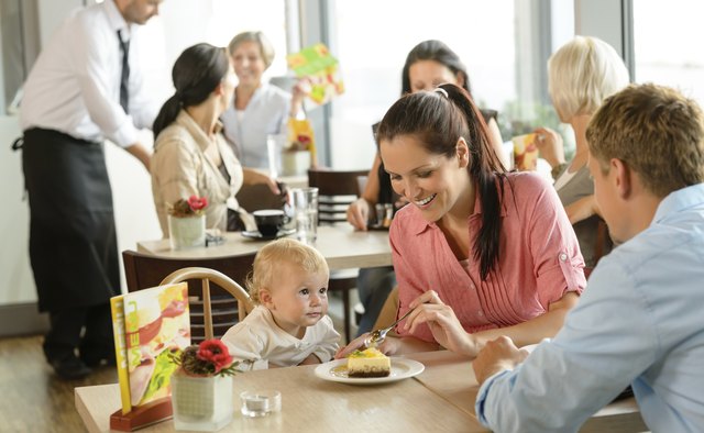 Couple feeding their child cake at cafe