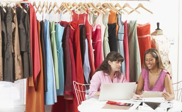 Two young women working on a laptop in a clothing store