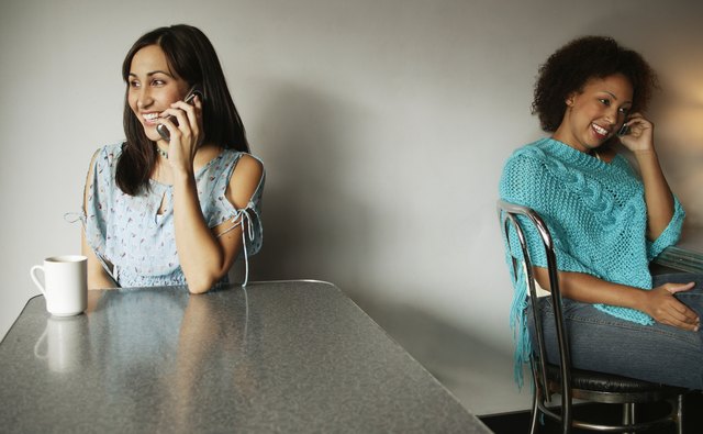 Portrait of two young women talking on mobile phones
