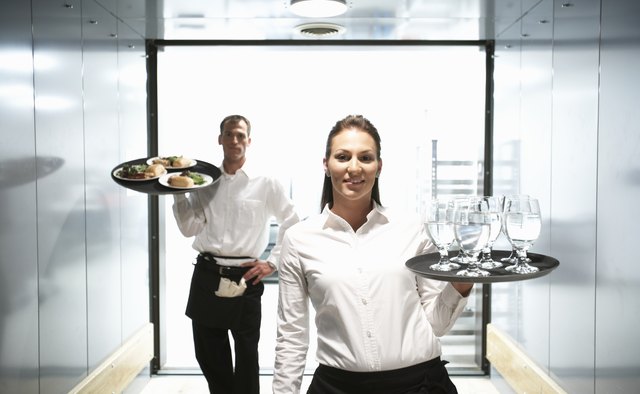 Waiter and waitress holding food and drink on trays, portrait