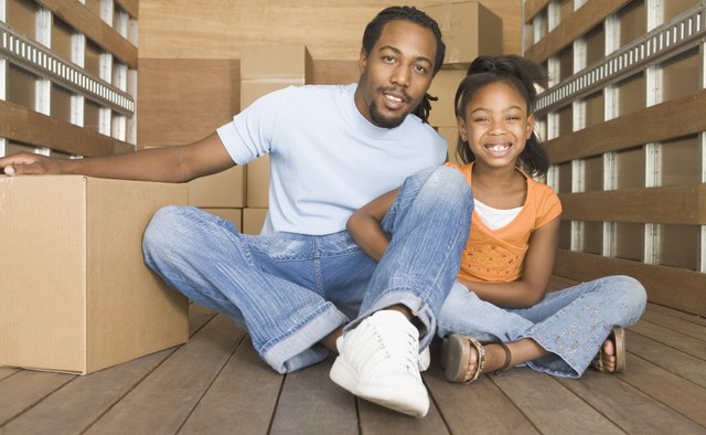 African father and daughter smiling in back of moving truck
