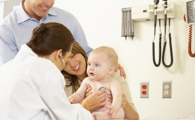 Side profile of a female doctor examining a baby boy with a stethoscope
