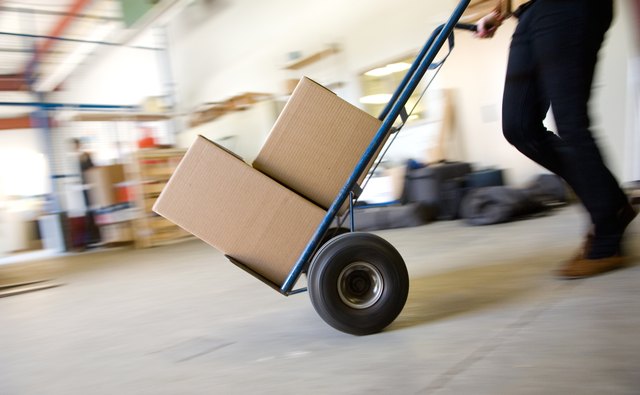 Person pushing hand truck across floor of warehouse