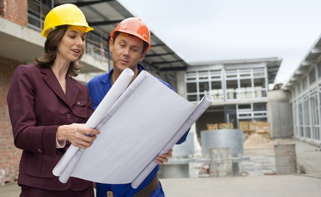 Businesswoman reading blueprints with foreman