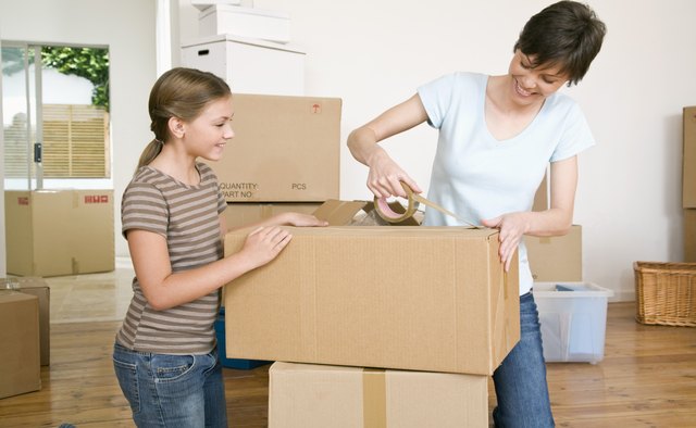 Woman and daughter taping moving boxes