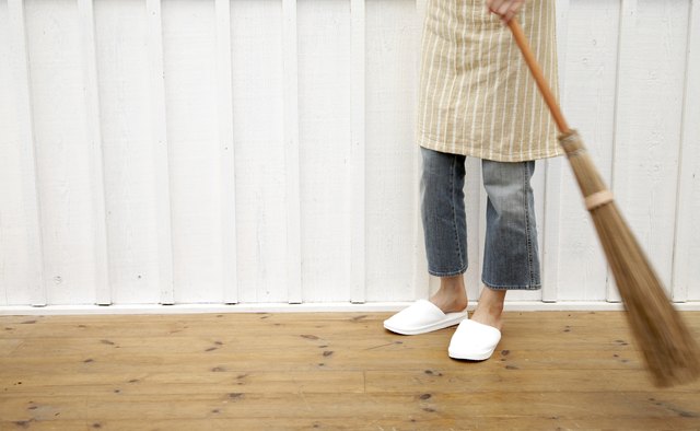 Woman sweeping floor using Japanese style broom in home
