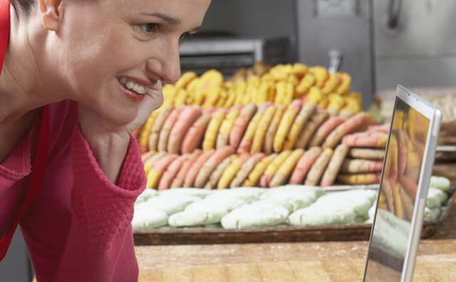 Side profile of a female baker operating a laptop in a bakery