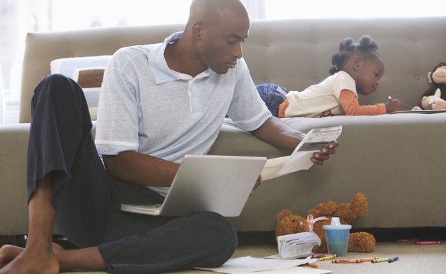 Father looking at paperwork by daughter (2-4) on sofa