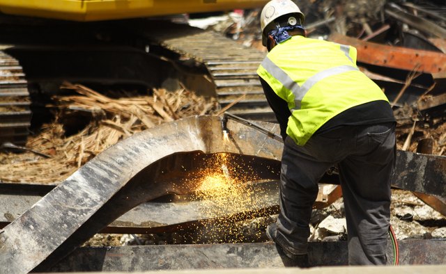 Construction Worker Cutting Scrap Metal Girder Sparks Building Demolition Site
