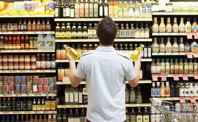 Young man looking at bottles of oil in market, rear view, close-up
