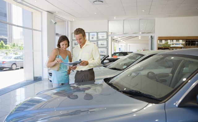Man and woman looking at brochure in car dealership