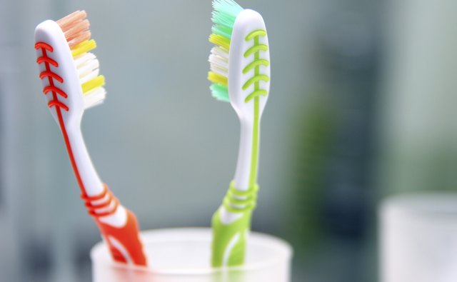 Two toothbrushes in the glass.