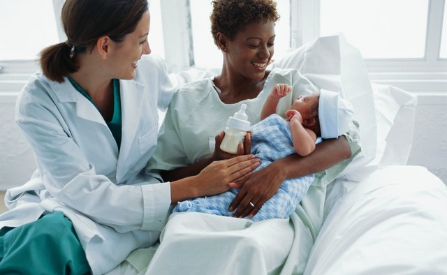 view of a doctor watching a new mother feed the baby with a bottle