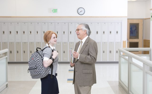 Head teacher talking with school girl (16-17) in school hallway