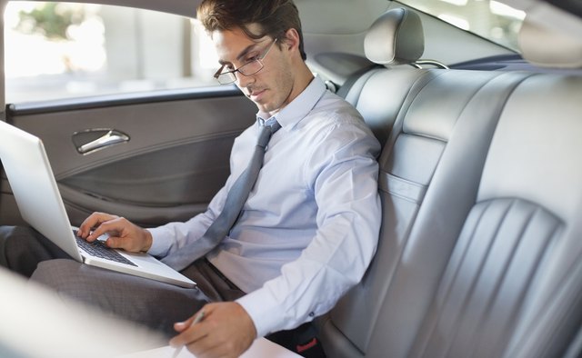 Businessman using laptop in back seat of car