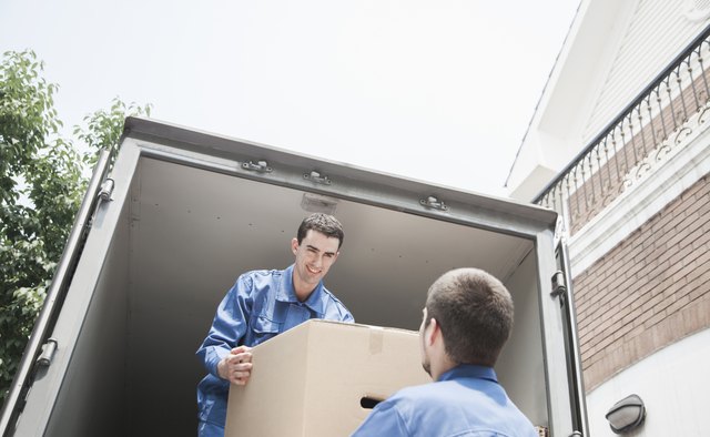 Movers unloading moving van, passing a cardboard box