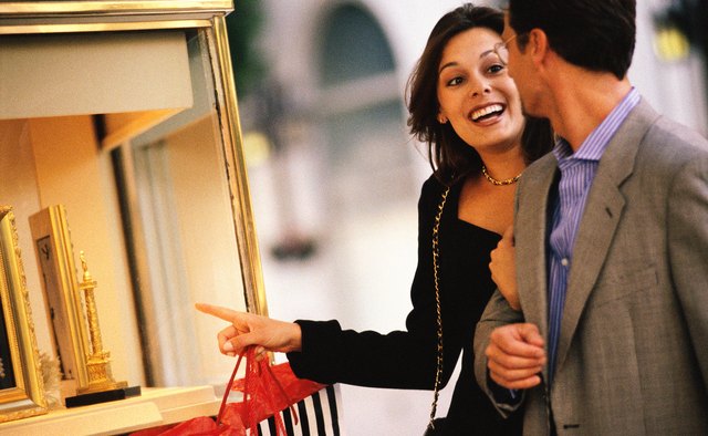 Woman pointing out display window at jewlrey store to man
