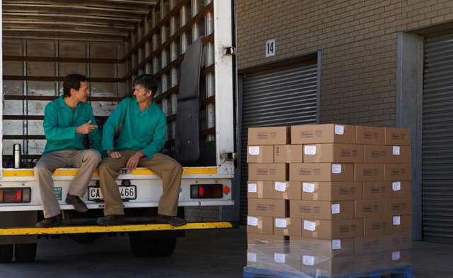 Two men sitting on lorry, with pallet