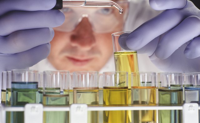 Chemist dropping liquid into test tubes, close-up