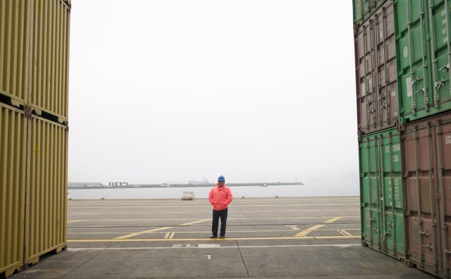 Man standing between containers in a shipping yard