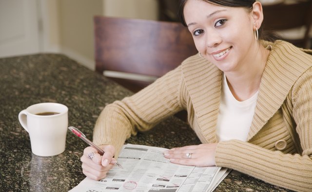 Hispanic woman searching newspaper classified ads