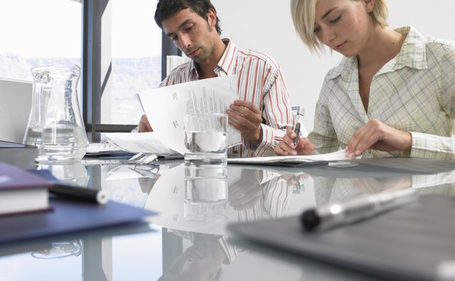 Businesswoman and man sitting at conference table reading documents