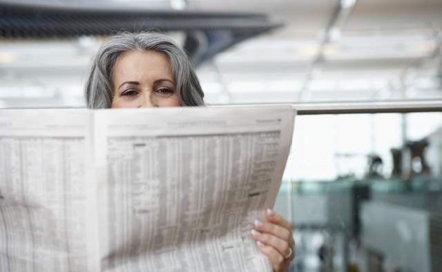 Mature businesswoman sitting in airport reading newspaper