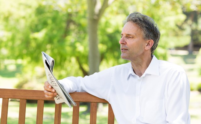 Businessman reading newspaper in park