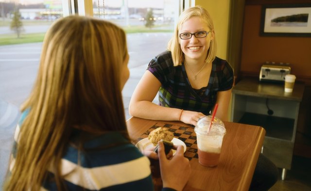 Two Women Talking At A Table In A Cafe