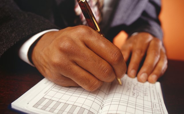 Businessman writing in chequebook, Close-up of hand
